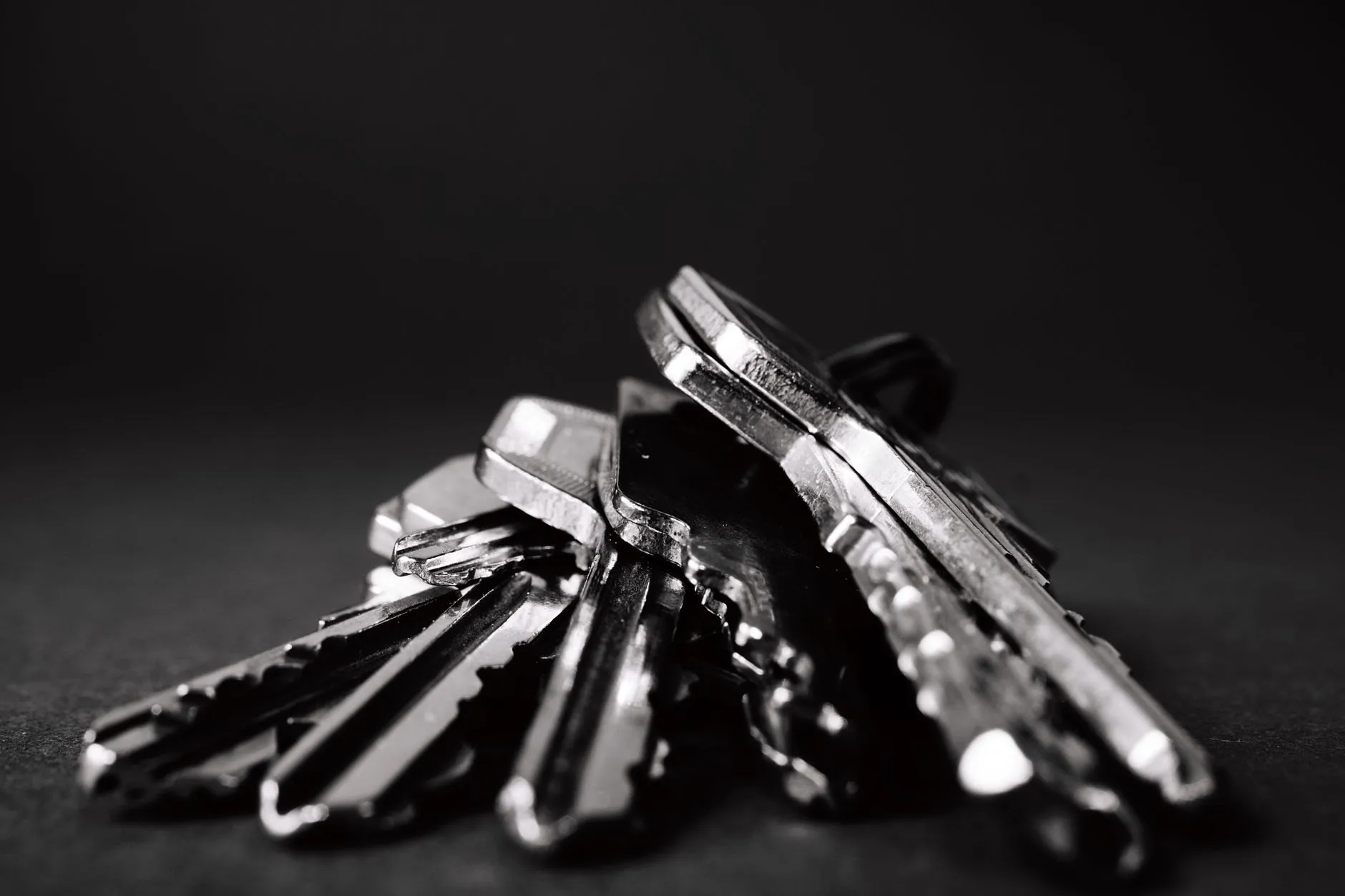 A bunch of door keys lying on a dark surface, close up